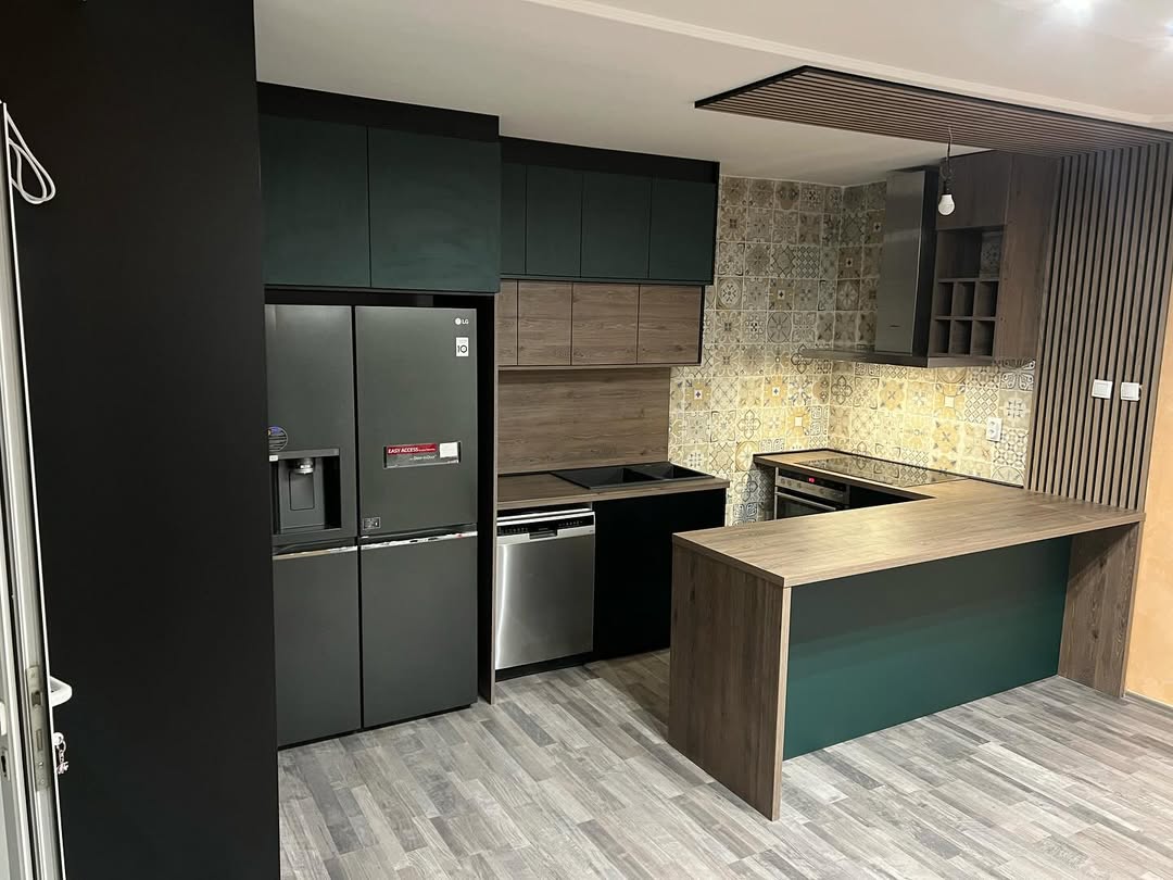 Modern kitchen with dark cabinets, patterned tile backsplash, wood accents, built-in appliances, and a large wooden island counter.